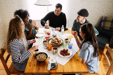 Hohe Winkel Ansicht der glücklichen Freunde genießen Essen auf dem Tisch zu Hause serviert - MASF13657