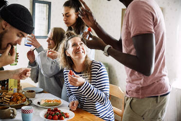 Glückliche Freunde genießen das Essen bei einem geselligen Beisammensein im Haus - MASF13664