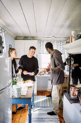 Glückliche Freunde unterhalten sich beim Essen in der Küche zu Hause - MASF13667