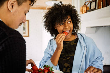 Friends eating strawberries while standing at home - MASF13668