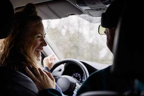 Fröhliche Frau im Gespräch mit einem männlichen Freund während der Fahrt im Auto - MASF13669