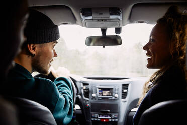 Male and female friends talking while traveling in car - MASF13673