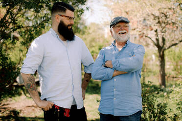 Smiling senior father and son standing in yard - MASF13687