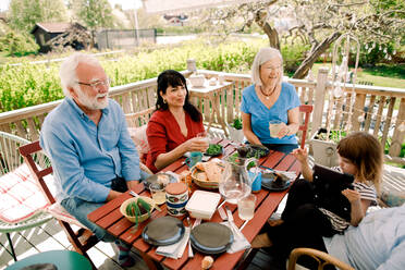 Multi-generational family enjoying food at table in patio - MASF13694