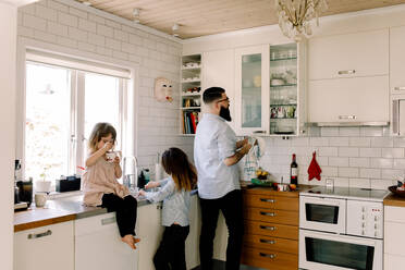 Vater und Tochter arbeiten am Tresen, während das Mädchen in der Küche isst - MASF13710