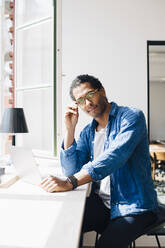 Portrait of male computer programmer sitting at desk in office - MASF13742