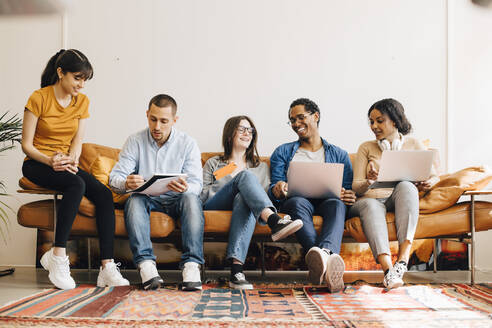 Glückliche Kollegen, die auf dem Sofa in einem kreativen Büro zusammenarbeiten - MASF13771