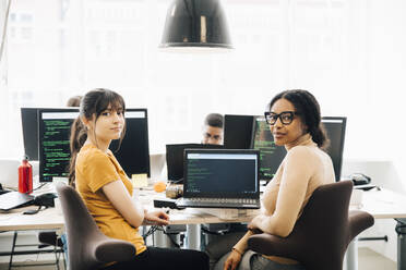 Portrait of female computer hackers sitting desk in creative office - MASF13807