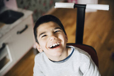 Hoher Blickwinkel auf einen glücklichen behinderten Jungen, der zu Hause im Rollstuhl sitzt - MASF13888