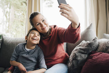 Mutter macht Selfie mit glücklichem autistischen Sohn, während sie zu Hause auf dem Sofa sitzt - MASF13906