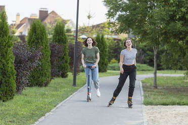 Glückliche Frauen Freunde Rollerblading und Reiten Push-Roller auf dem Bürgersteig - FSIF04336