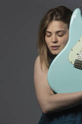 Porträt heitere junge Frau mit E-Gitarre - FSIF04338