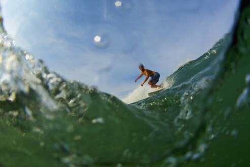Männlicher Surfer reitet auf einer Meereswelle - FSIF04340