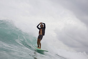 Männlicher Surfer reitet auf einer Meereswelle - FSIF04383