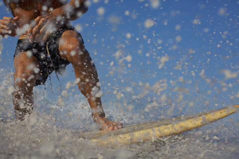 Männlicher Surfer reitet auf einer Welle und spritzt, lizenzfreies Stockfoto