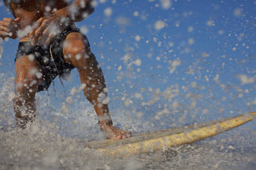 Männlicher Surfer reitet auf einer Welle und spritzt - FSIF04384