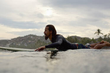 Männlicher Surfer paddelt auf dem Meer - FSIF04387