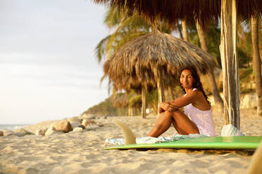Porträt einer selbstbewussten Surferin mit Surfbrett, die sich am sonnigen Strand entspannt, Sayulita, Nayarit, Mexiko - FSIF04408