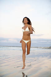 Frau im Bikini läuft im nassen Sand am Strand - FSIF04419