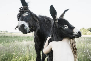 Bare Chested Girl umarmt Baby Esel in ländlichen Feld - FSIF04429