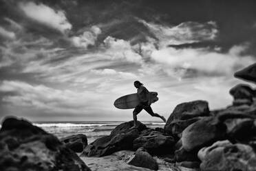 Männlicher Surfer mit Surfbrett am felsigen Meeresstrand, Higuera Blanca, Nayarit, Mexiko - FSIF04437