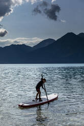 Junge beim Paddeln auf einem sonnigen, idyllischen See, Walchensee, Bayern, Deutschland - FSIF04439