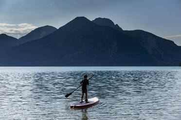 Junge beim Paddeln auf einem sonnigen, idyllischen Bergsee, Walchensee, Bayern, Deutschland - FSIF04440