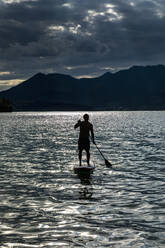 Silhouette Mann beim Paddeln auf einem sonnigen, idyllischen See, Walchensee, Bayern, Deutschland - FSIF04441