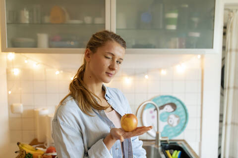 Porträt einer jungen Frau, die zu Hause einen Apfel hält, lizenzfreies Stockfoto