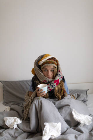 Ill young woman drinking tea in bed at home stock photo