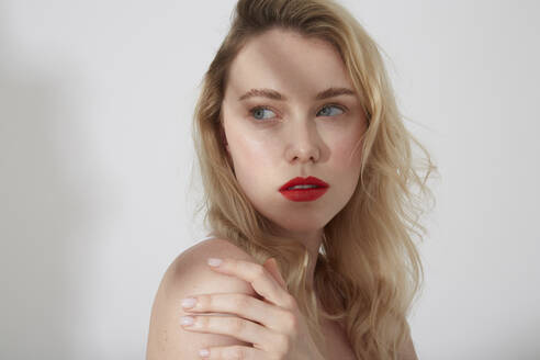 Portrait of young blond woman with red lips and shadow on her face - PGCF00017