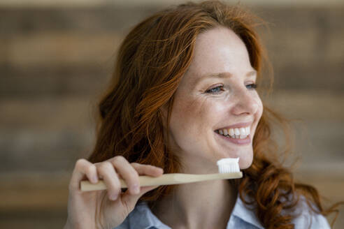 Portrait of laughing redheaded woman with toothbrush - KNSF06519