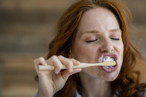 Portrait of redheaded woman brushing teeth - KNSF06520
