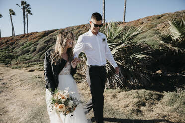 Glückliche Braut und Bräutigam auf einem Weg an der Küste - LHPF00783