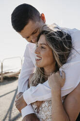 Happy bride and groom hugging outdoors - LHPF00786