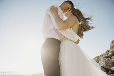 Affectionate bride and groom on the beach at sunset - LHPF00807