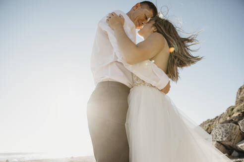 Verliebte Braut und Bräutigam am Strand bei Sonnenuntergang - LHPF00807