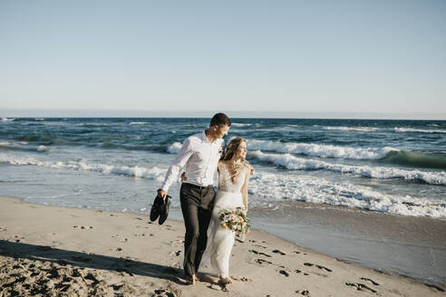 Bride and groom walking on the beach - LHPF00811