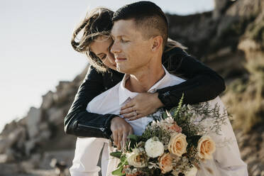 Affectionate bride embracing groom at the coast - LHPF00813