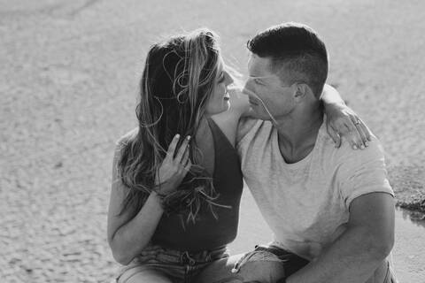 Verliebtes junges Paar am Strand sitzend, lizenzfreies Stockfoto