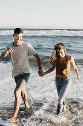 Glückliches junges Paar beim Laufen am Meeresufer - LHPF00832