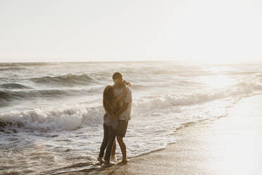 Affectionate young couple hugging at the seashore at sunset - LHPF00833