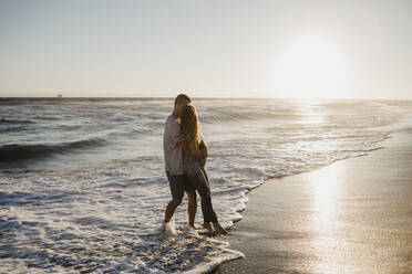 Affectionate young couple hugging at the seashore at sunset - LHPF00835