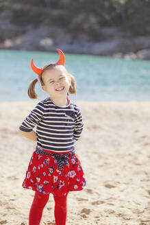 Portrait of girl standing on the beach wearing devil's horns - XCF00203