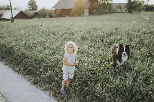 Mädchen geht mit Hund auf dem Lande spazieren - DWF00493