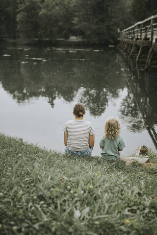 Mutter und Tochter sitzen am Flussufer, lizenzfreies Stockfoto