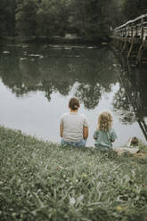 Mother and daughter sitting at riverside - DWF00503