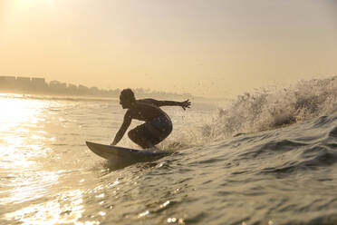 Surfer auf einer Welle bei Sonnenuntergang - KNTF03395