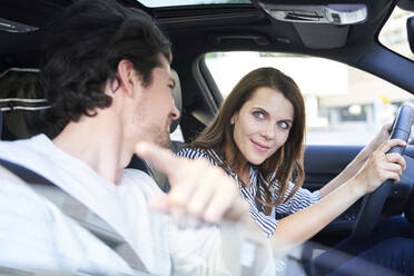 Happy couple in a car with woman driving and man pointing his finger - PNEF01979