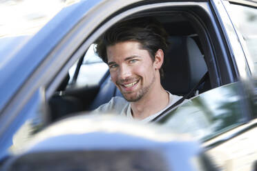 Portrait of smiling man driving car - PNEF01986